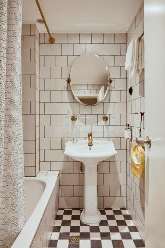 a bathroom with a sink and a tub and a mirror at Max Brown Hotel Midtown, part of Sircle Collection in Düsseldorf