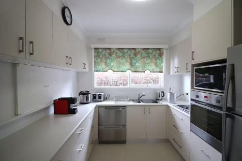a white kitchen with white cabinets and a window at Rosebud Comfort Retreat in Rosebud