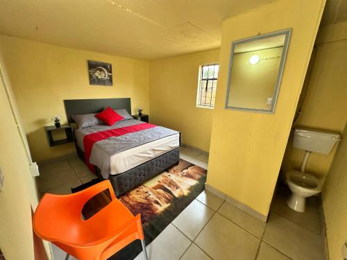 a bedroom with a bed and a orange chair at SleepCozyGuestHouse in Soweto