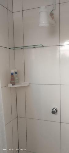 a white tiled shower with a shelf in a bathroom at Pousada Flor do deserto - Mandacaru in Santo Amaro