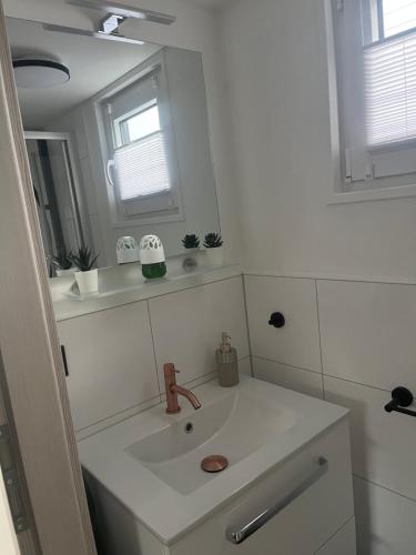 een witte badkamer met een wastafel en een spiegel bij Hausboot - Nordsonne 10 in Wangerland