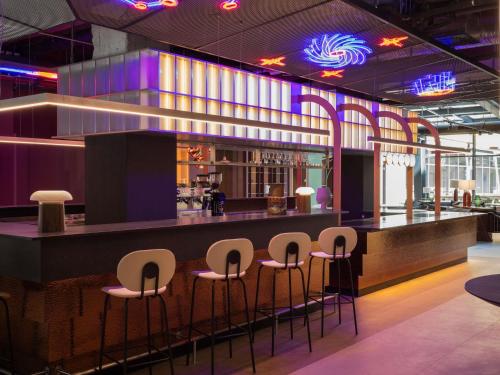 een bar met krukken in een restaurant met paarse verlichting bij You Hotel Budapest - Handwritten Collection in Boedapest