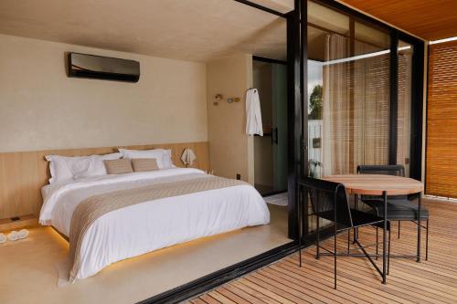 a bedroom with a large bed and a table at Bowi Hotel Conceito in Tiradentes