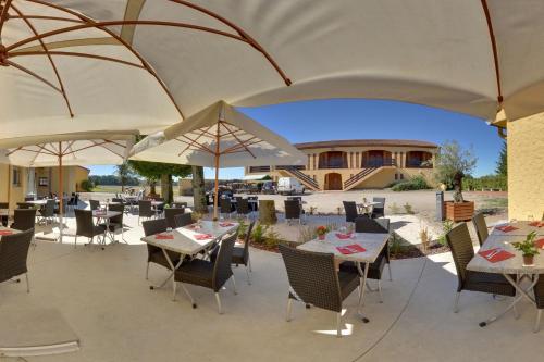 un patio avec des tables, des chaises et des parasols dans l'établissement Logis L'Auberge du Gros, à Silly-sur-Nied
