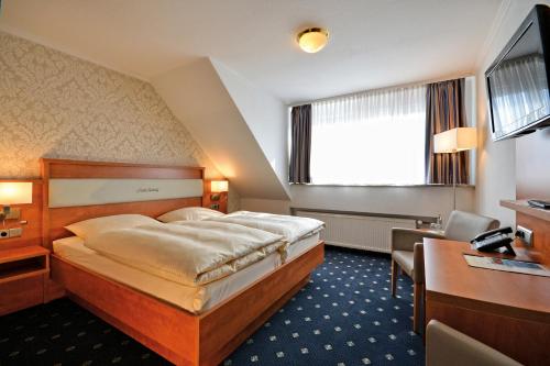 a hotel room with a bed and a desk at Landgasthaus & Hotel Lindenhof in Königslutter am Elm