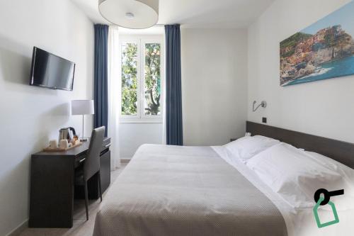 a bedroom with a bed and a desk and a window at Hotiday La Spezia Centrale in La Spezia