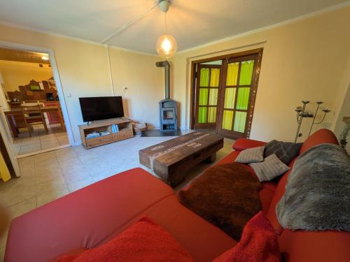 un soggiorno con un divano rosso e una TV di Fewo Kerzenzimmer - Märchen aus Wachs und Flamme a Garvensdorf