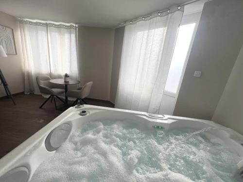 una grande vasca da bagno in una stanza con tavolo di L'Hakuna II - Suite et Spa a Fontaine-Notre-Dame