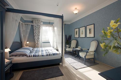 a bedroom with a bed and two chairs and a window at Haus Waldesruh - Eventhotel in Schönewalde