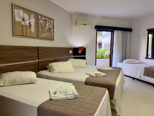 a hotel room with two beds and two tables at Pousada Larimor in Boicucanga