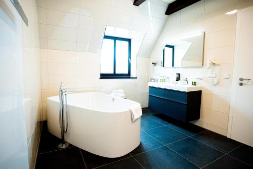 een witte badkamer met een bad en een wastafel bij Farmer Hotel Basedow & Spa in Basedow