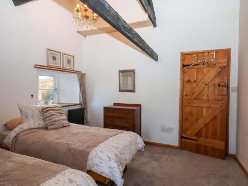 a bedroom with two beds and a wooden door at Park Cottage in Kingsbridge