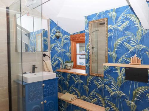 a blue bathroom with a sink and a mirror at Park Cottage in Kingsbridge