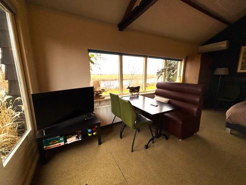 a room with a table and a television and a bedroom at Gastenhuisje De Donk in Brandwijk