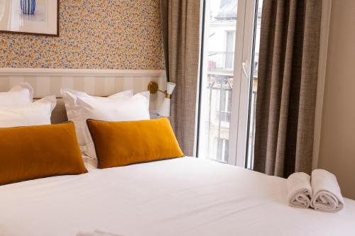 a bedroom with a bed with yellow pillows and a window at Joli Môme in Paris
