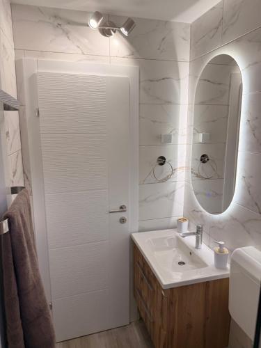 a white bathroom with a sink and a mirror at Apartman Andrea in Brčko