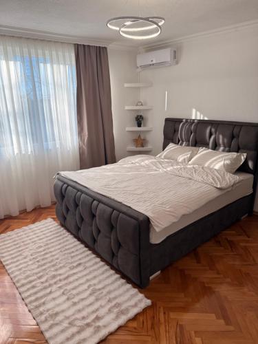 a bedroom with a large bed with a leather headboard at Apartman Andrea in Brčko