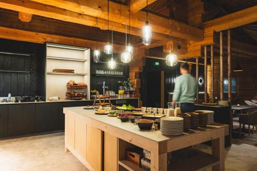 a man in a kitchen with a table with dishes at Vaattunki Wilderness Resort in Rovaniemi