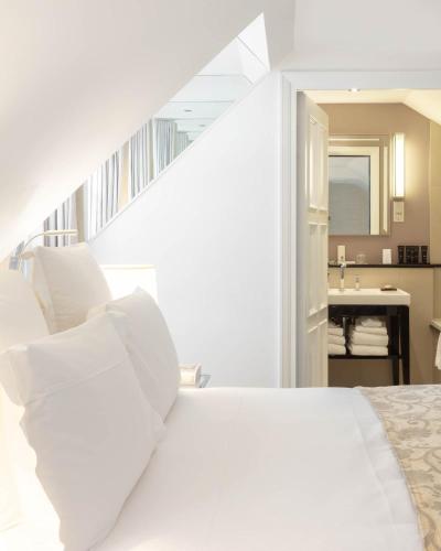 a white bed with white pillows in a bedroom at Le Burgundy Paris in Paris