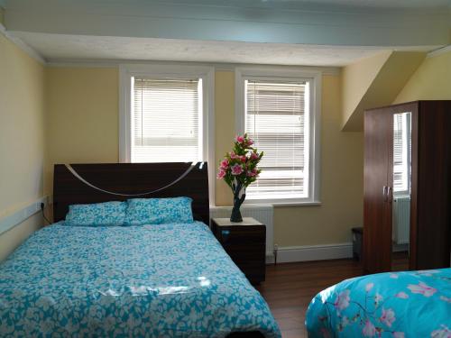 a bedroom with a bed and a vase of flowers at SS Sunrise & Silk in Bognor Regis