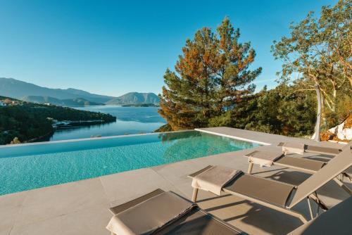 a pool with chairs and a view of the water at Kohyli Villas in Meganisi