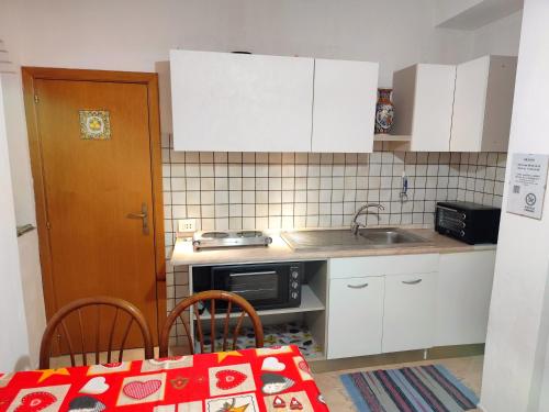een kleine keuken met een spoelbak en een magnetron bij La Casa Di Via Marzulli in Acireale
