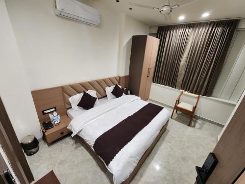a bedroom with a large bed and a chair at Den Inn in Hisār
