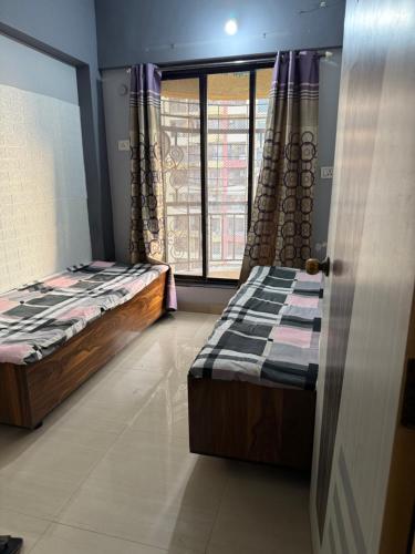 two twin beds in a room with a window at Riyas stay in Mumbai