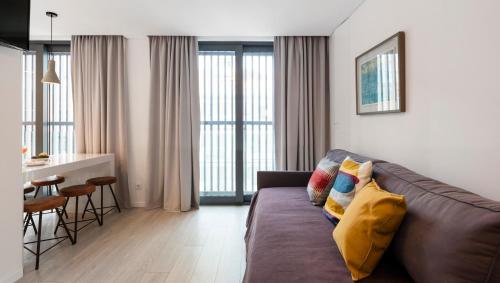 a living room with a brown couch and a kitchen at Lisbon Serviced Apartments - Parque in Lisbon