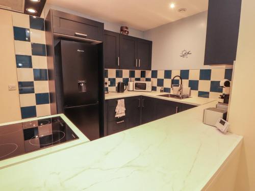 a kitchen with black cabinets and a marble counter top at 20 Lorton Street in Cockermouth