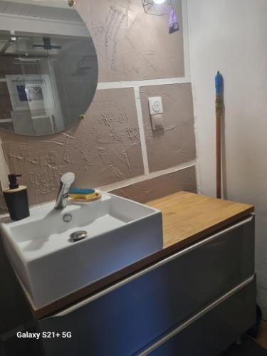 een badkamer met een witte wastafel en een spiegel bij Chez Marilou in Arcens