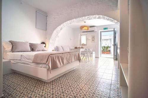 a white bedroom with a large bed and a kitchen at Suite Amalaya Κατώι in Kithnos