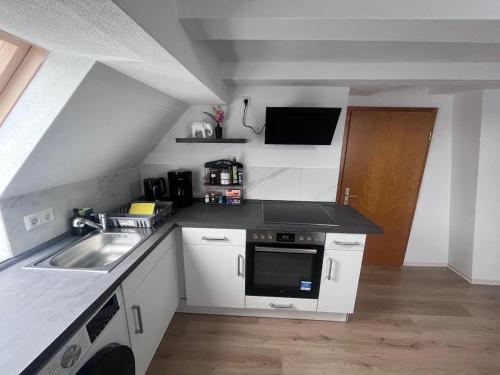 eine kleine Küche mit Spüle und Herd in der Unterkunft Team at Home Gemütliches Dachgeschossapartment in Blaubeuren