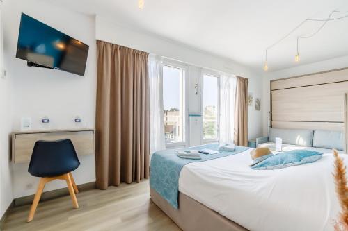 a bedroom with a bed and a tv and a chair at Hotel La Cote Oceane - CLIMATISÉ - Saint Jean de Monts- 250m plage in Saint-Jean-de-Monts