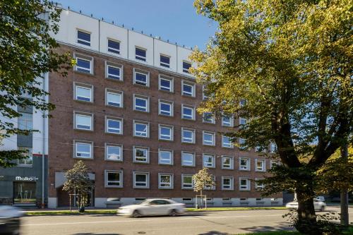 Ein weißes Auto fährt vor einem Backsteingebäude in der Unterkunft Balcia Residence in Riga