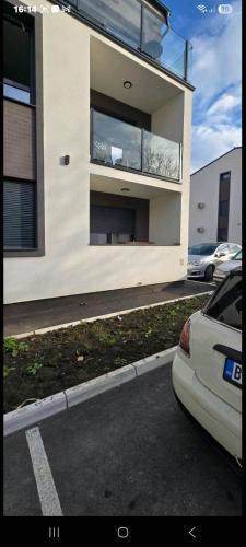 een witte auto geparkeerd voor een gebouw bij Aerodrom apartman in Ledine