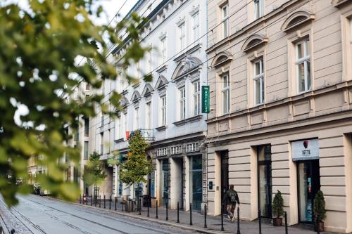 a person walking down a street in front of buildings at Hotel 32 Kraków Old Town in Krakow