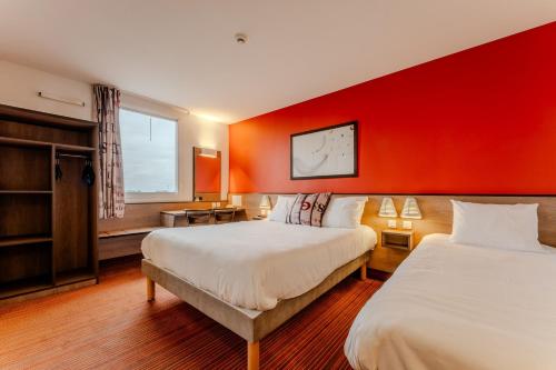 a hotel room with two beds and a red wall at Ace Hotel Poitiers in Poitiers