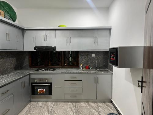 a kitchen with white cabinets and a stove top oven at Kaarasaaram inn in Avarankal