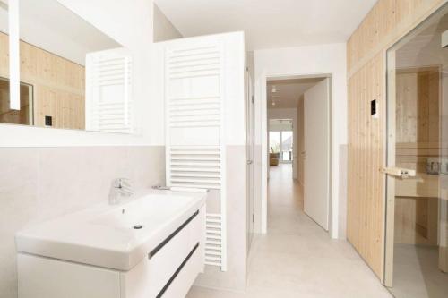 a white bathroom with a sink and a mirror at Dahmer Strand 5 in Dahme