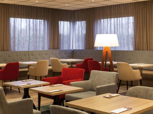 a restaurant with tables and chairs and a lamp at Mercure Hotel Amsterdam West in Amsterdam
