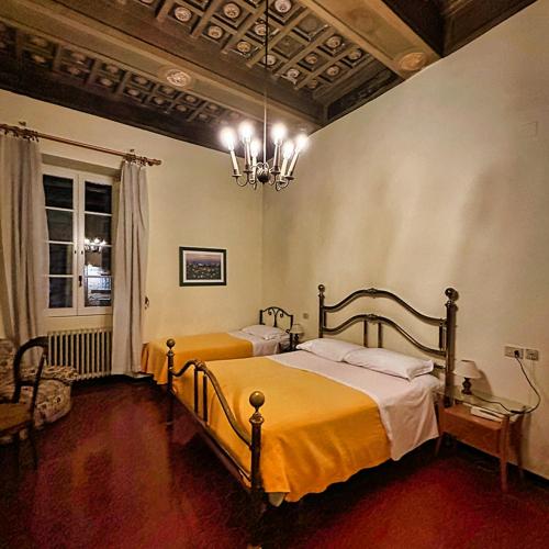 a bedroom with two beds and a chandelier at Albergo Anna in Perugia