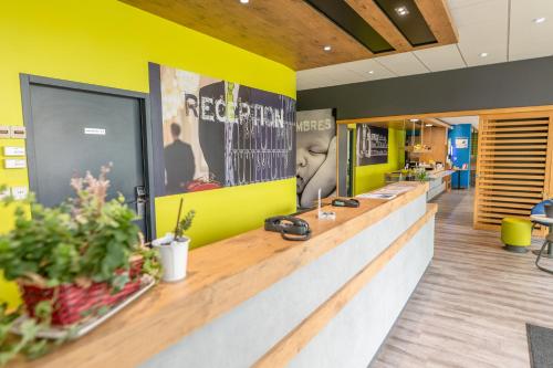 een receptiebalie in een winkel met gele muren bij Ibis budget Brest Sud Plougastel - Hôtel rénové in Plougastel-Daoulas