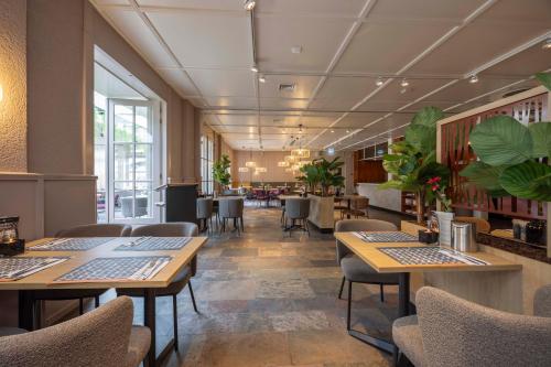 a restaurant with tables and chairs and plants at Fletcher Hotel Restaurant Victoria-Hoenderloo in Hoenderloo