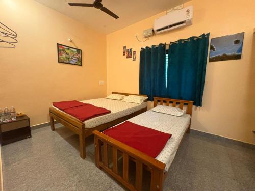 een kamer met 2 aparte bedden en een ventilator bij Areca Nest in Gokarna