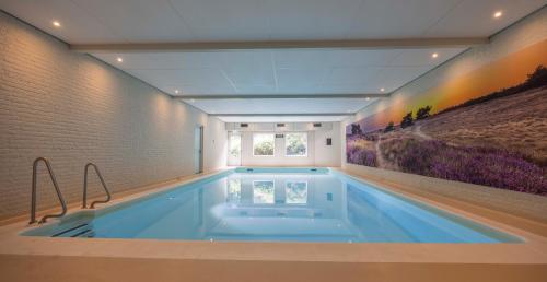 a large swimming pool in a room with a painting on the wall at Fletcher Hotel Restaurant Victoria-Hoenderloo in Hoenderloo