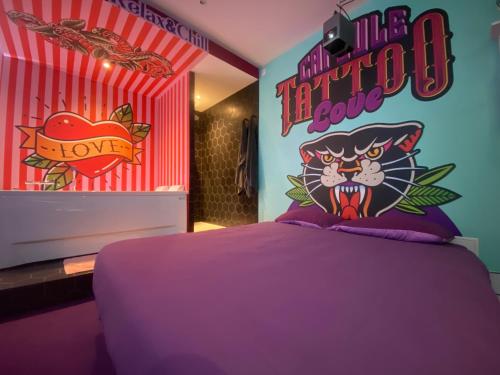 une chambre avec un lit violet et un panneau Hello Kitty dans l'établissement Capsule Tattoo Love, à Douai