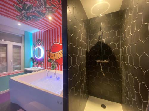 une salle de bain avec une grande baignoire ornée d'un personnage de dessin animé sur le mur dans l'établissement Capsule Tattoo Love, à Douai