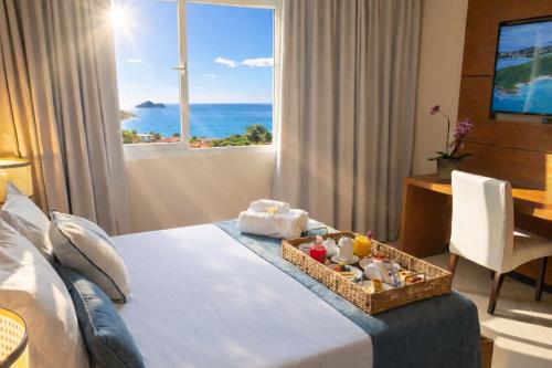 a hotel room with a bed with a view of the ocean at Buzios Mar Hotel in Búzios