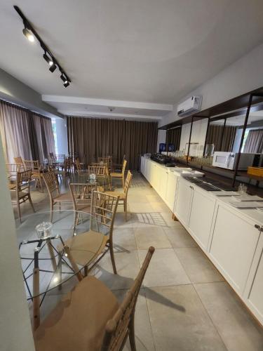a large room with tables and chairs and a kitchen at Murano Suits Hotel in João Pessoa